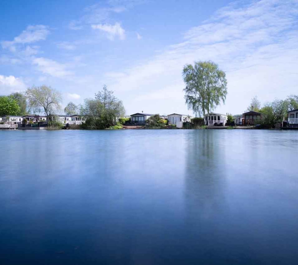 A photo of a riverside horizon during dawn of a row of static caravans. image