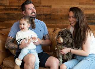 A family enjoying an afternoon bite to eat at The Lookout Bar & Eatery, Retallack. There is a mother and father, a young girl and their dog sat on the sofa. image