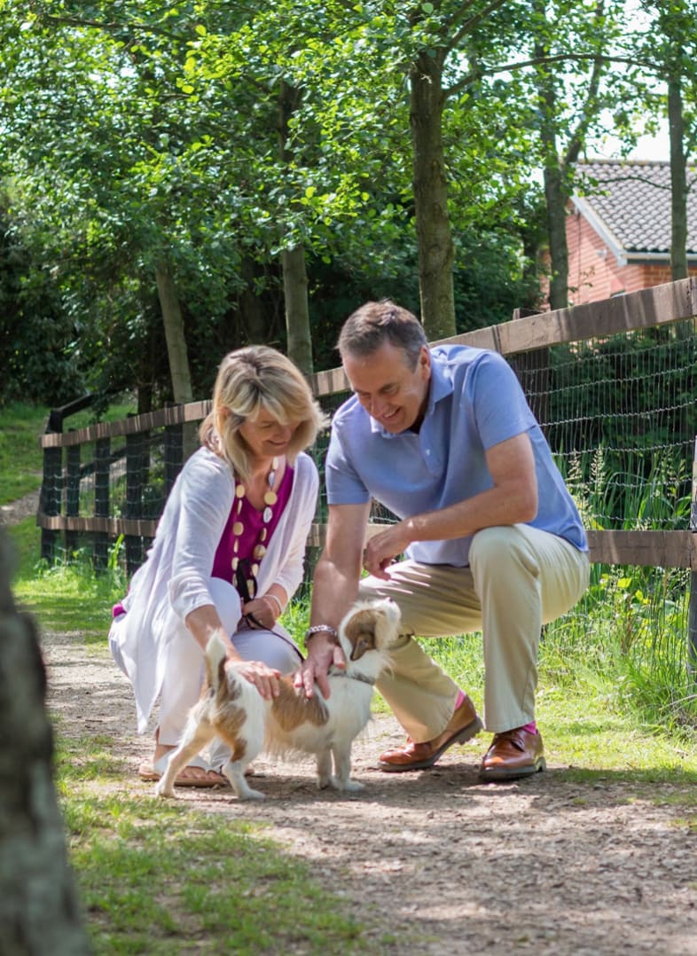 A couple playing with a dog at our holiday park.