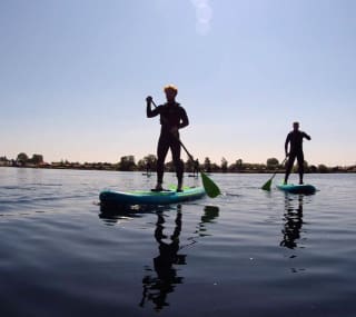 A photo of two people paddle boarding in the calm lake at our Tattershall Lakes holiday park. image