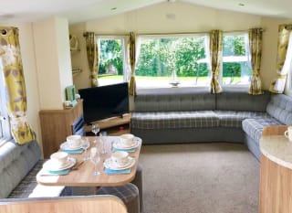 The interior of one of our Superior caravan holiday homes. There’s a large sofa, flatscreen TV, and a comfortable dining area. image