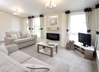 The interior of one of our Luxury holiday lodges. There are two large sofas, a TV, and plenty of space around a coffee table. image