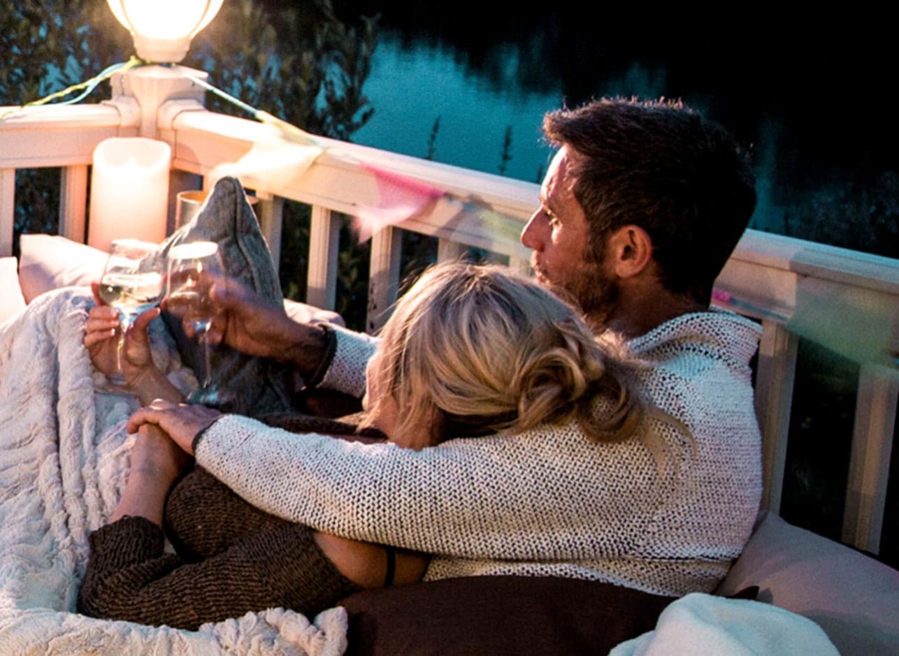 A couple sitting outside their holiday home with a drink of wine. image