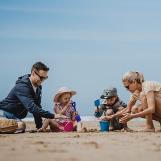 A family enjoying a summers day on the beach. There is a mother and father and two young children. image