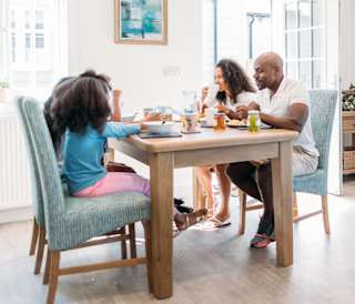 A family enjoying a meal together at the table in one of our stunning holiday homes.