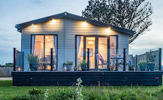 A photo of a static caravan with the patio doors facing the camrea. The photo is taken durng a sunset. image