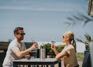 A couple sat outside enjoying a glass of wine together at The Sunset Bar and Eatery, Newperran, on a summers day. image