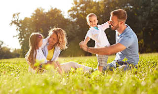 A young family playing in the grass outside on a sunny day.