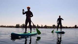 A photo of two people paddle boarding in the calm lake at our Tattershall Lakes holiday park.