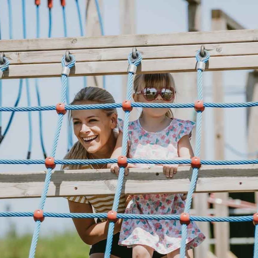 A mother and daughter playing in our adventure playground on a sunny day.