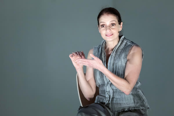 Mulher de cabelos presos e roupas cinzas