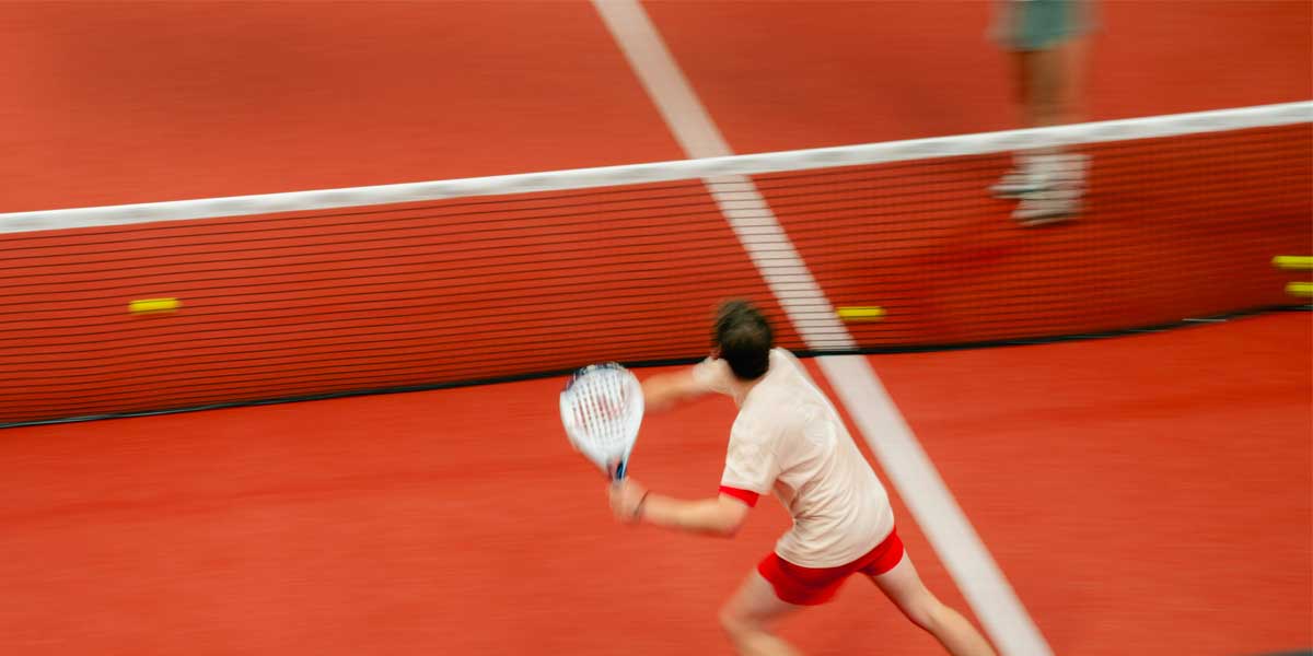 Padel player on red court