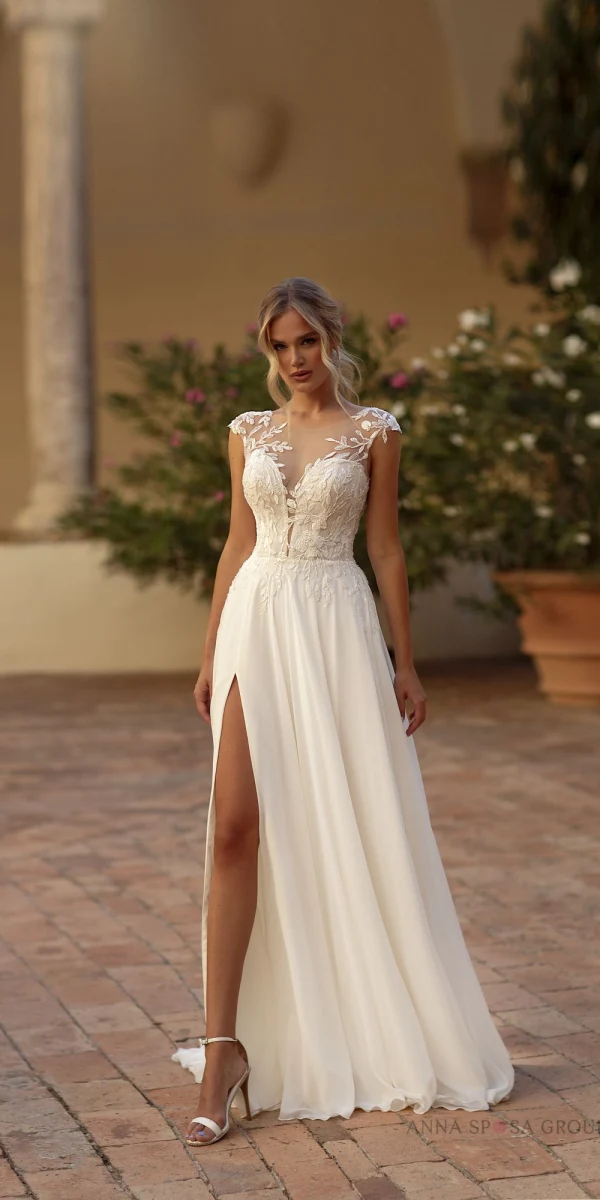 Robe de mariée Tina avec un bustier en dentelle illusion et une jupe fluide fendue, idéale pour une mariée moderne et élégante.