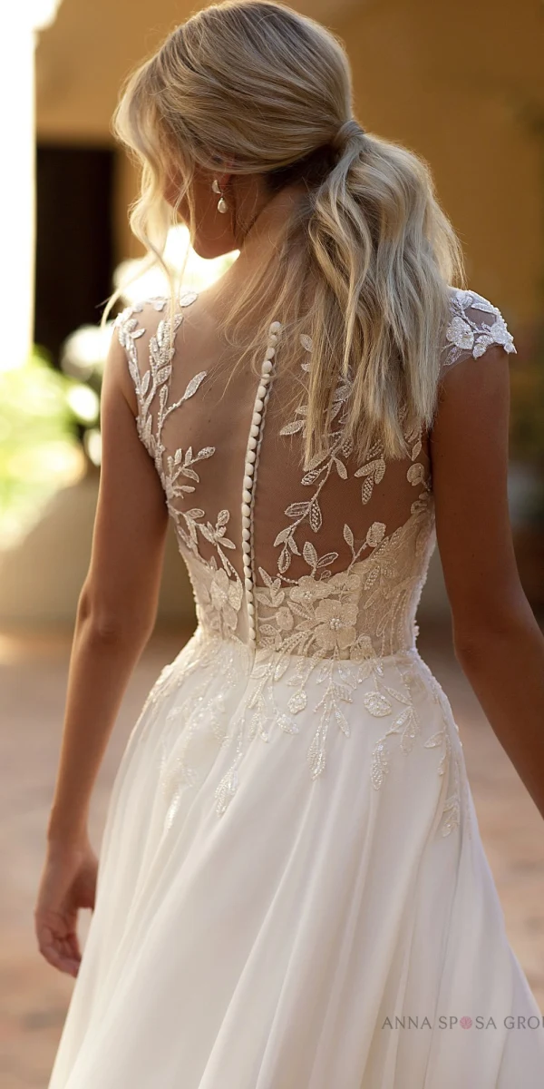 Robe de mariée Tina avec un bustier en dentelle illusion et une jupe fluide fendue, idéale pour une mariée moderne et élégante.