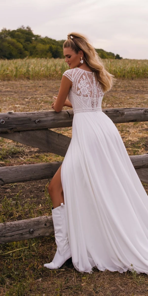 Robe de mariée Lolita avec bustier en dentelle ajourée, manches courtes transparentes et jupe fluide fendue, bohème et élégante.