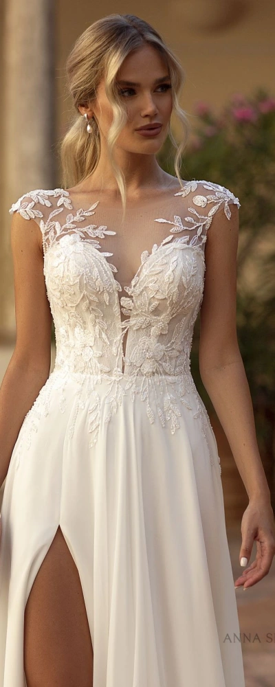 Robe de mariée Tina avec un bustier en dentelle illusion et une jupe fluide fendue, idéale pour une mariée moderne et élégante.