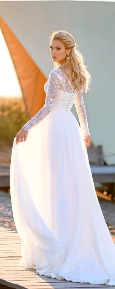Robe de mariée Anelisa avec manches longues en dentelle, jupe fluide fendue et décolleté profond, élégante et moderne.