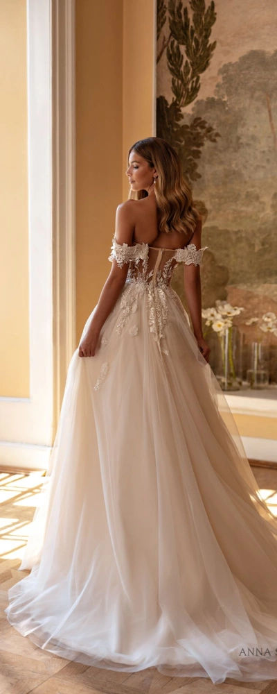 Vue de dos de la robe de mariée Constellation montrant la traîne fluide et les détails de dentelle sur la jupe - Création bohème chic.