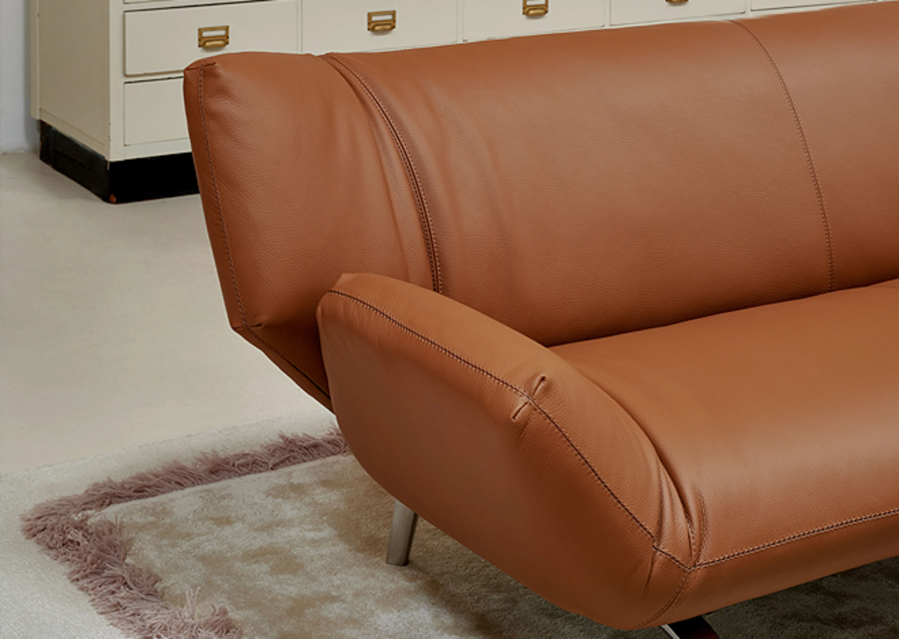 Braune Ledercouch, die auf einem Teppich sitzt