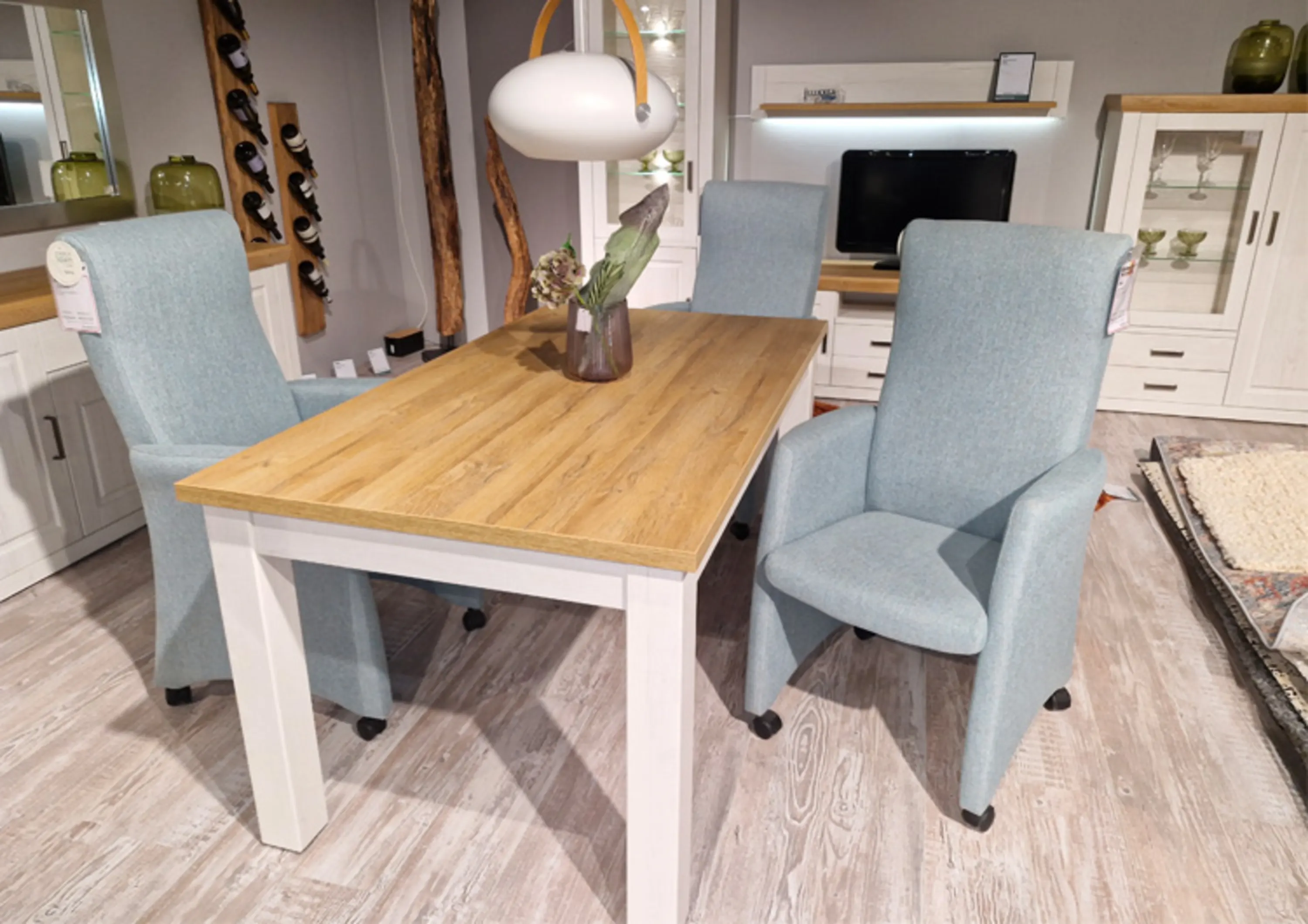 Drei hell blaue Sessel mit Rollen an einem Esstisch