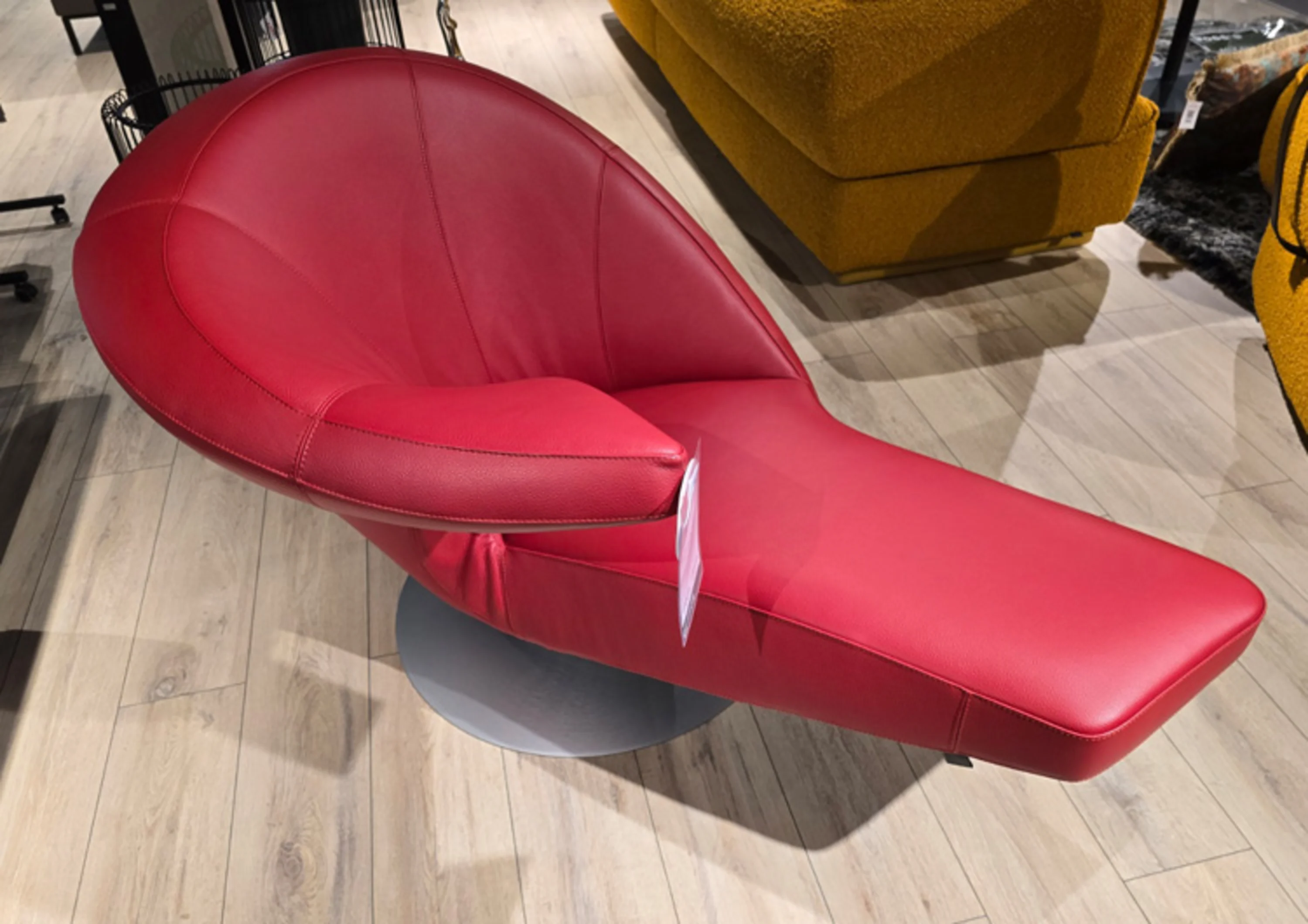 Roter Sessel mit einer Armlehne auf der rechten Seite und Fußablage.
