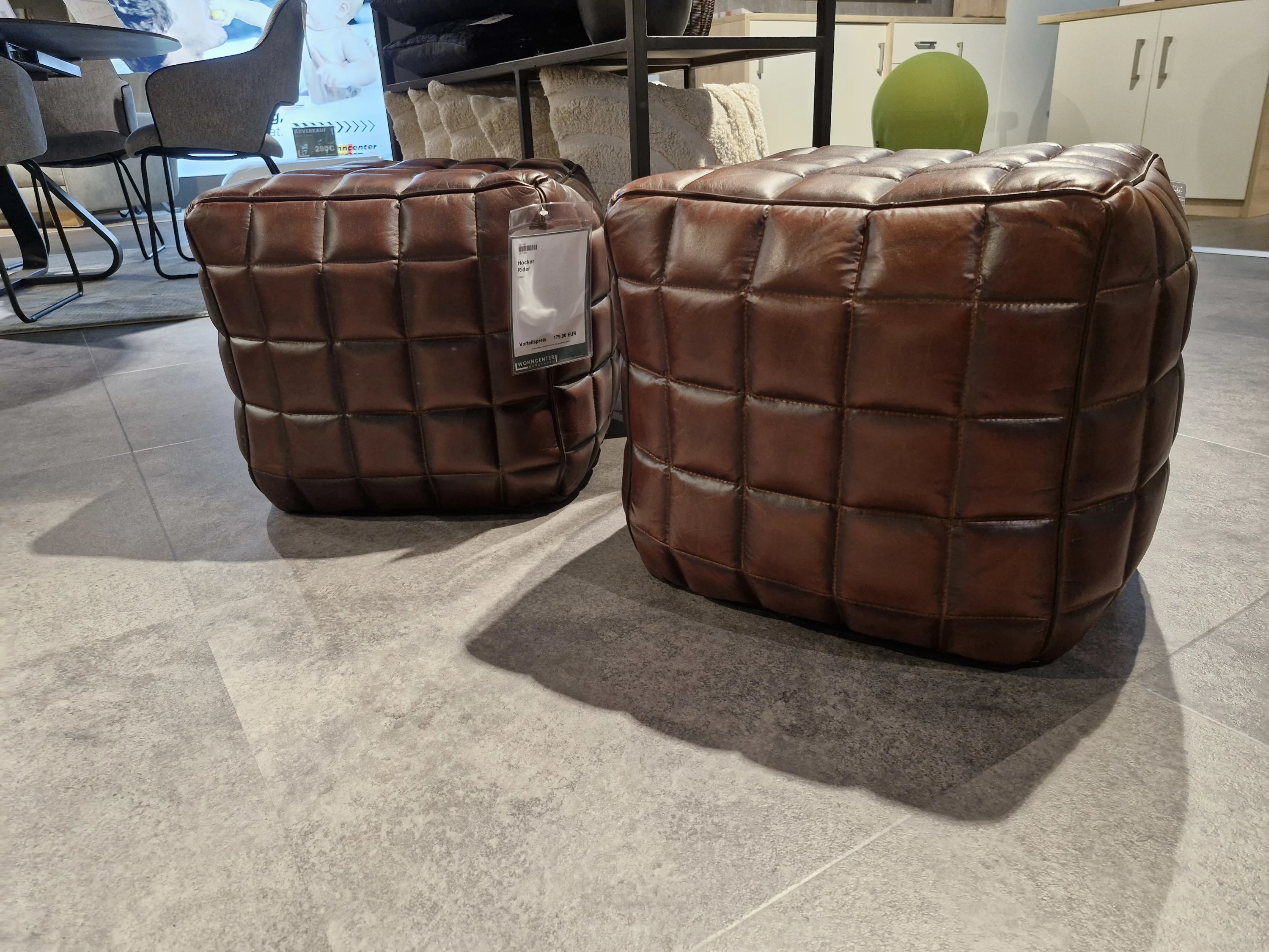 Zwei braune Leder Ottomanen sitzen auf einem Boden