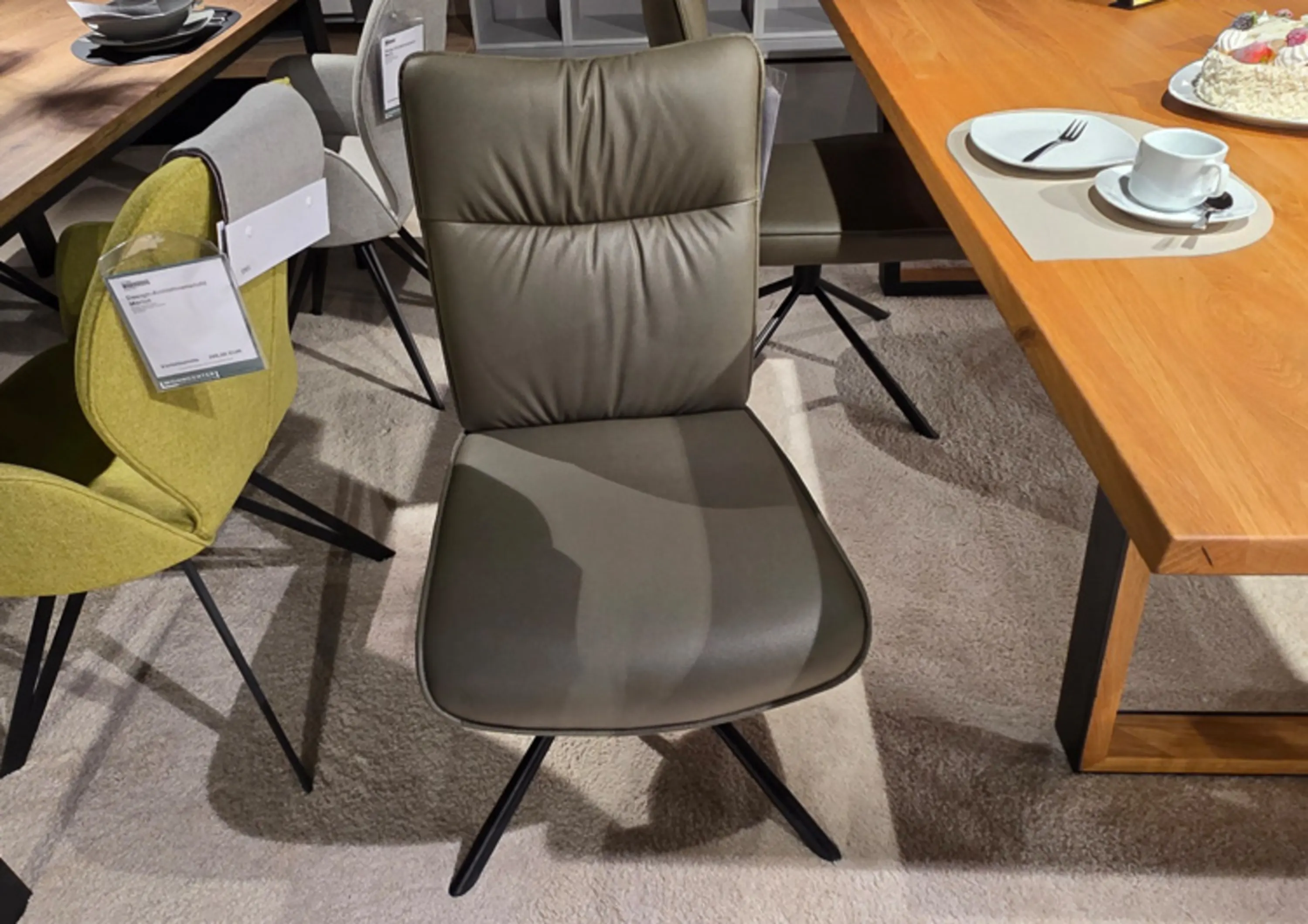 Moderner Polsterstuhl in elegantem Olive mit komfortabler Rückenpolsterung und drehbarem schwarzem Metallgestell, der stilvolles Design mit hohem Sitzkomfort verbindet.