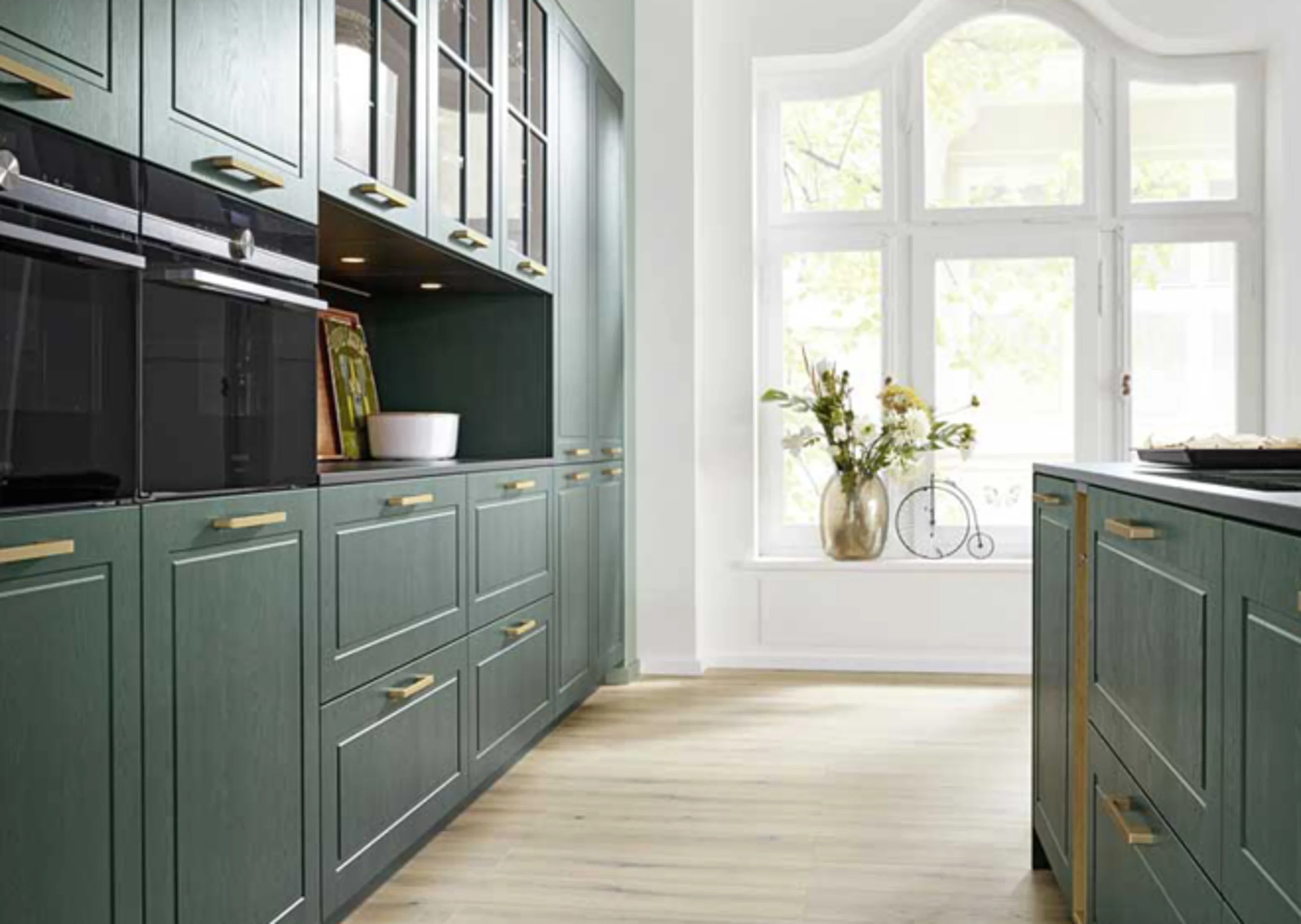 Küche mit grünen Schränken und einer weißen Wand