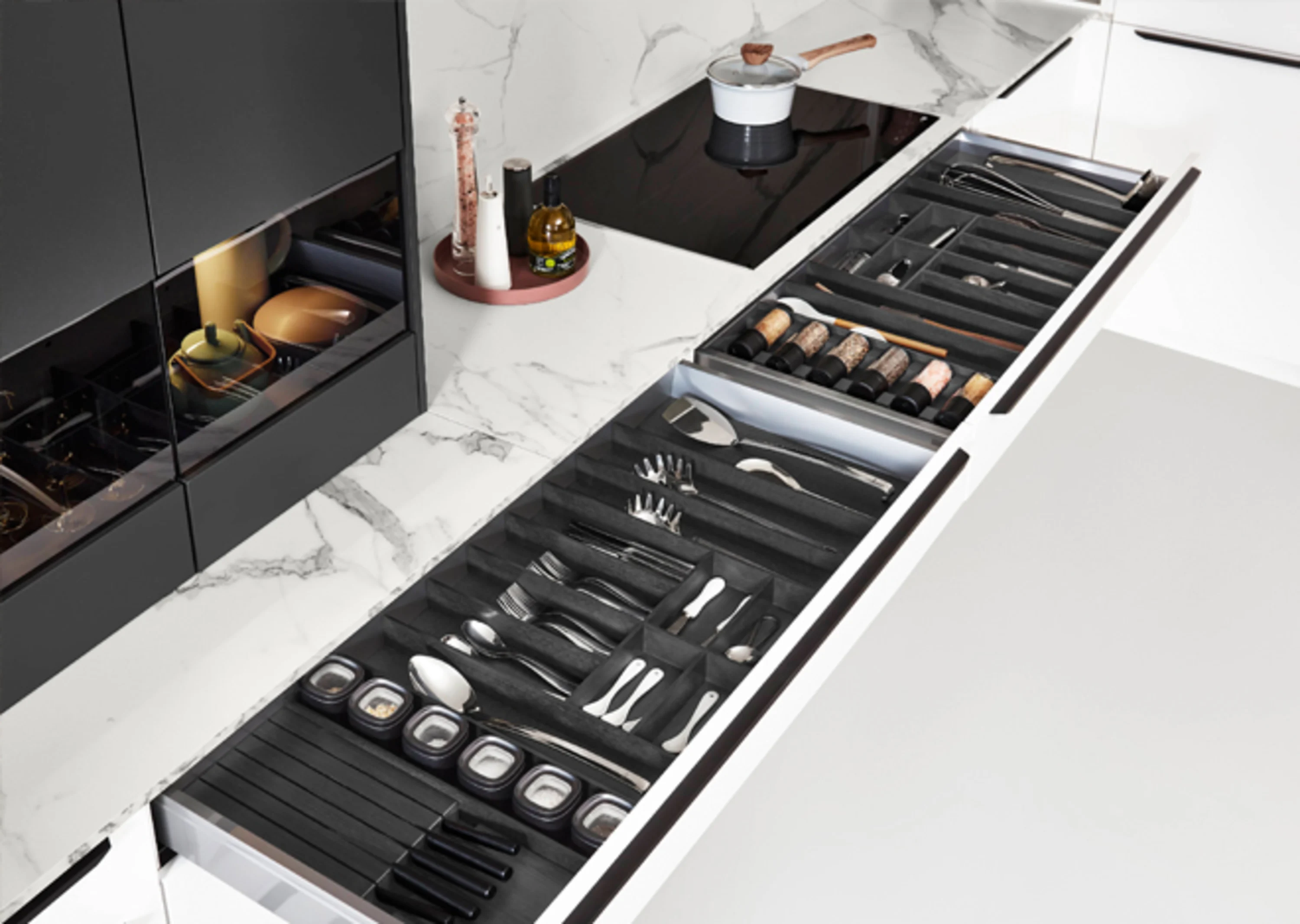 L-Küche in schwarz weiss mit Spüle in der Insel - Detailansicht Schubkästen und Kochfeld