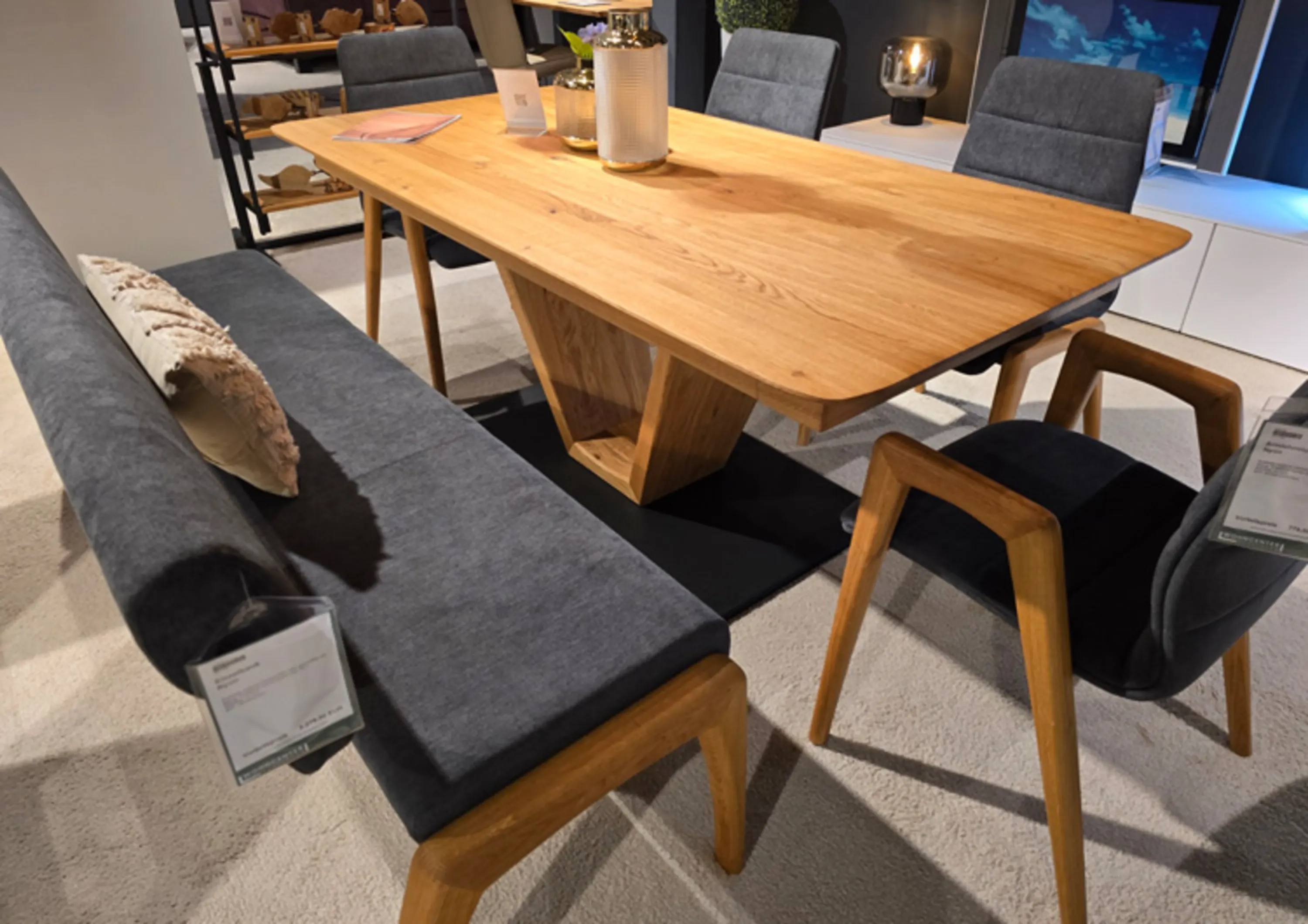 Holztisch mit schwarzem Gestell eine Bank und mehrere Stühle mit Holzgestell und Sitz und Rücken mit Stoff bezogen