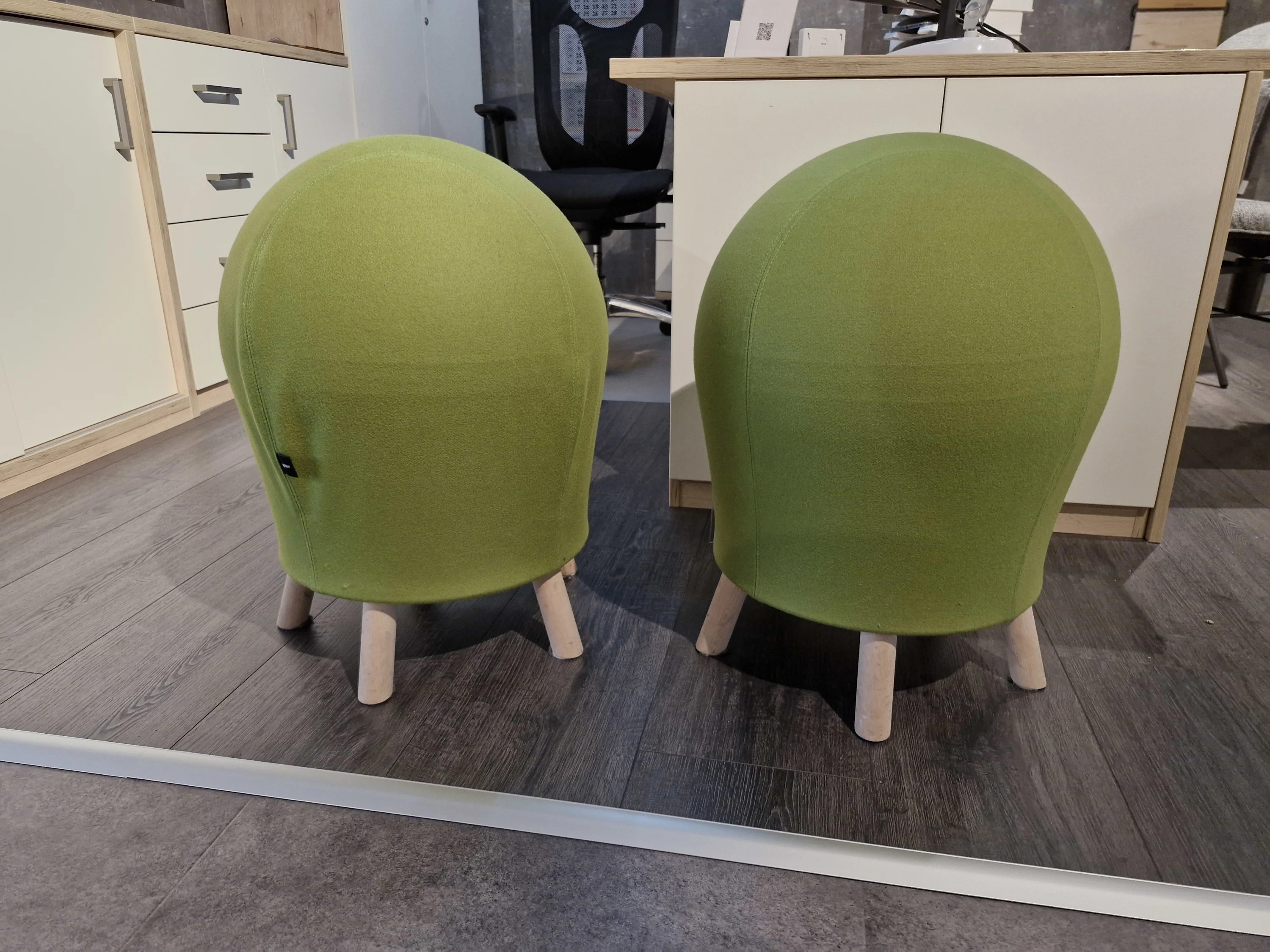 Zwei grüne Stühle sitzen auf einem Holzboden