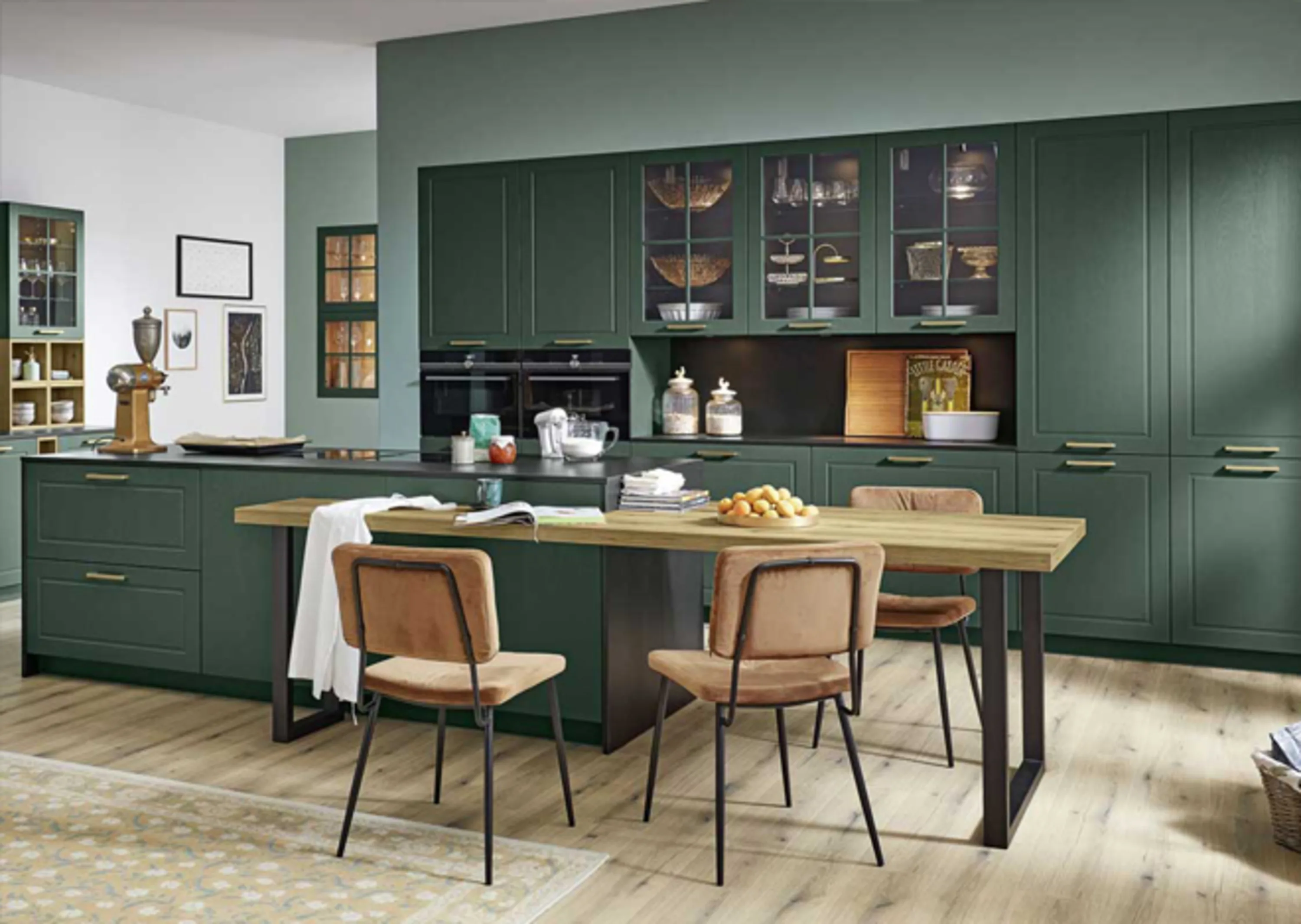 Küche mit grünen Schränken und einem Holztisch