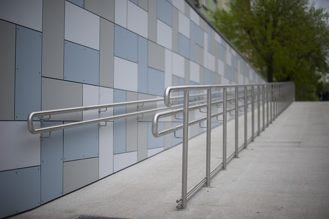 A smooth concrete ramp next to a building with handrails on both sides