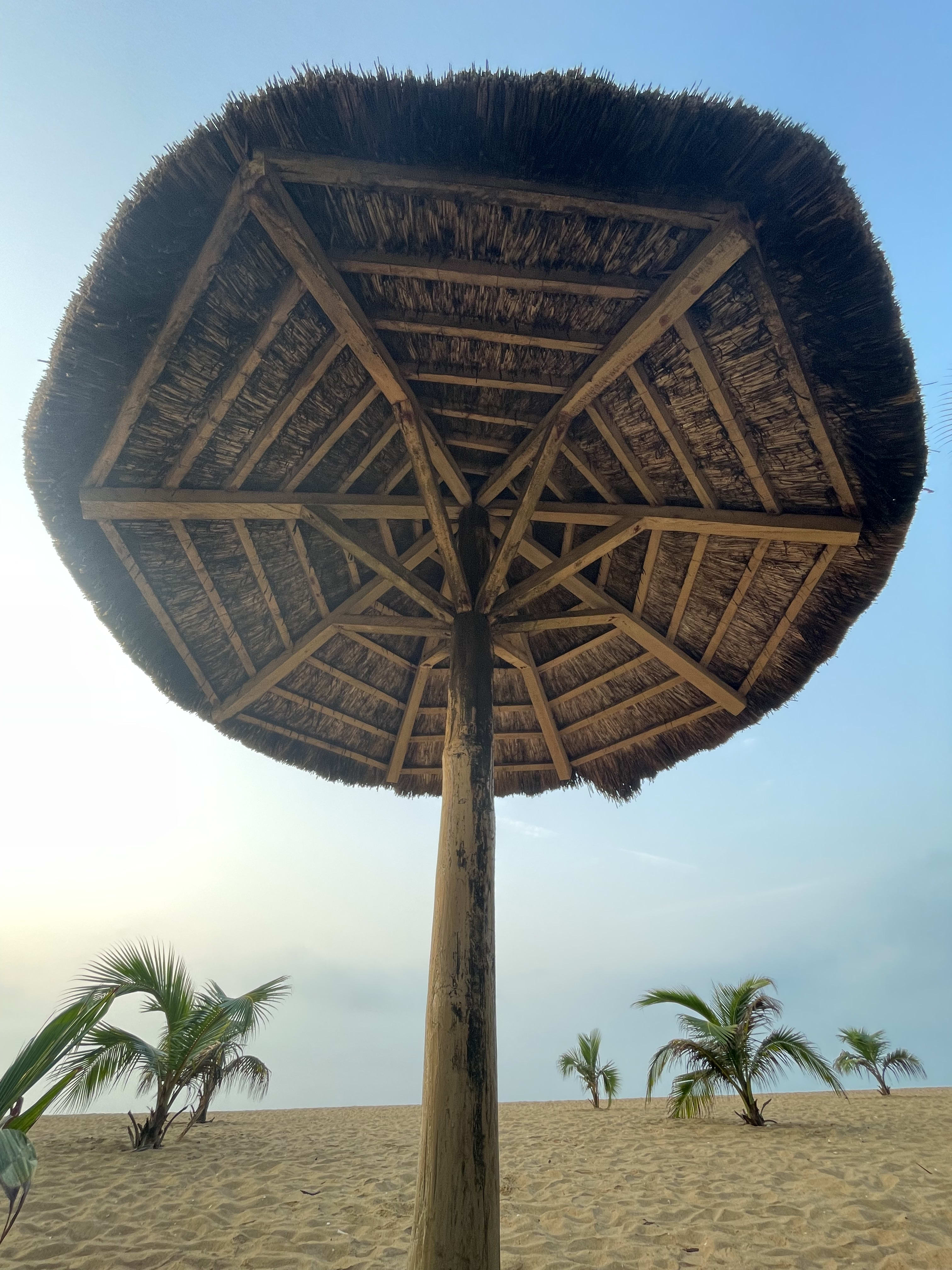 A thatched sun shade made out of dried coconut leaves and bamboo stick.