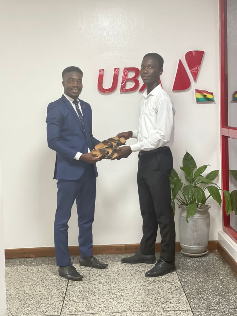 Edward Asare receiving a pair of Tomus sandals
