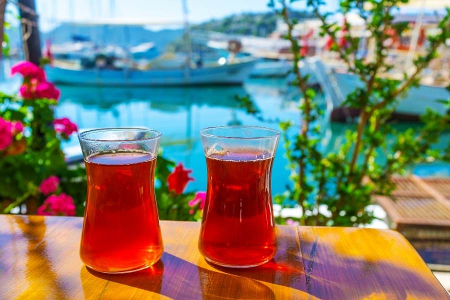 two glasses of Turkish tea on the table with a seaside background in Kaş