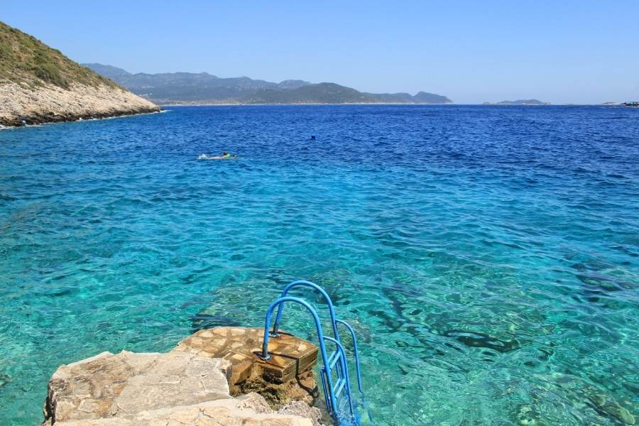 seascape in kas with a rock platform and a ladder going down into the sea at the forefront