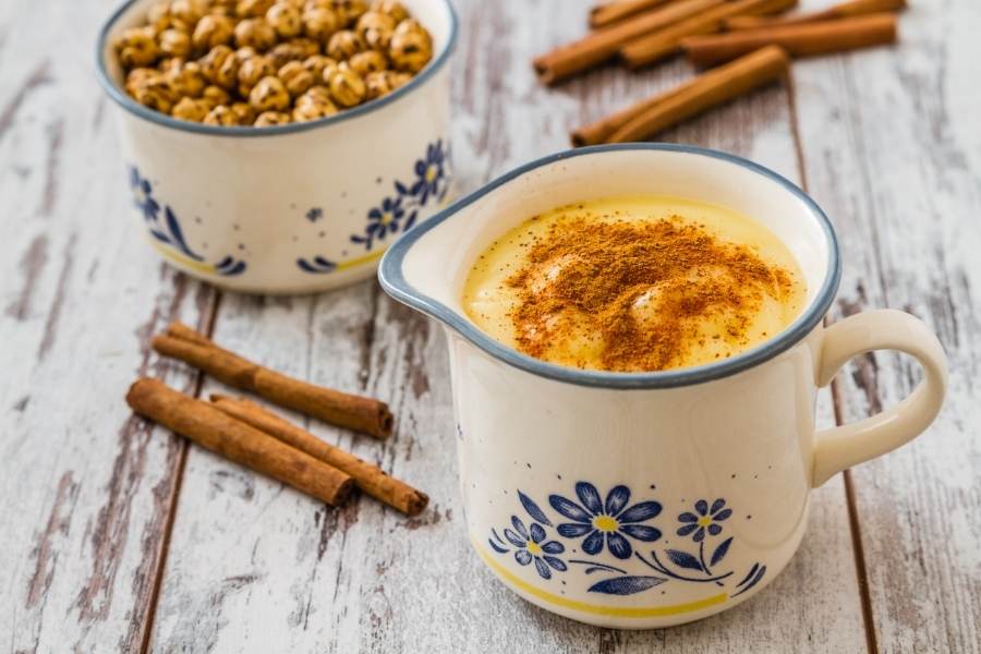 boza drink in two enamel cups with cinnamon sticks