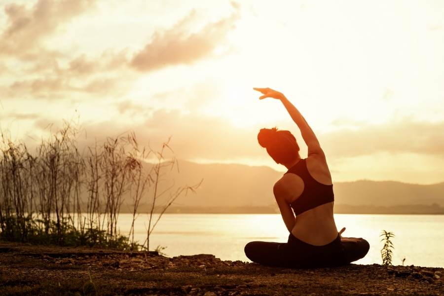 woman doing yoga at the beach at dusk