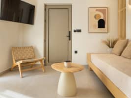 Modern minimalist living room with a neutral sectional sofa, round coffee tables, and illuminated wall shelving.