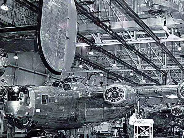 Workers standing next to a tank and an old Ford automobile in the Chester warehouse
