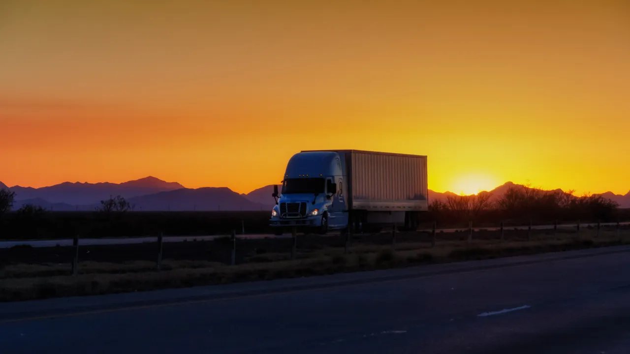 Semi truck driving on a highway at sunrise