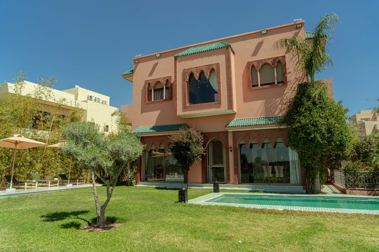 Villa Argan Golf courtyard at dusk with warm interior lighting through floor-to-ceiling glass windows