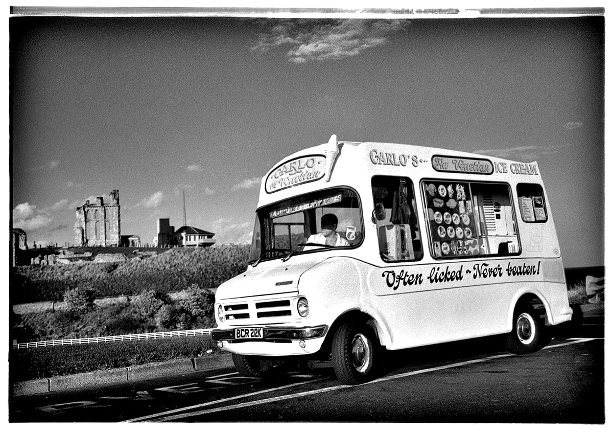 Carlo's ice cream van parked at Tynemouth with the Priory ruins visible in the background — Often Licked, Never Beaten