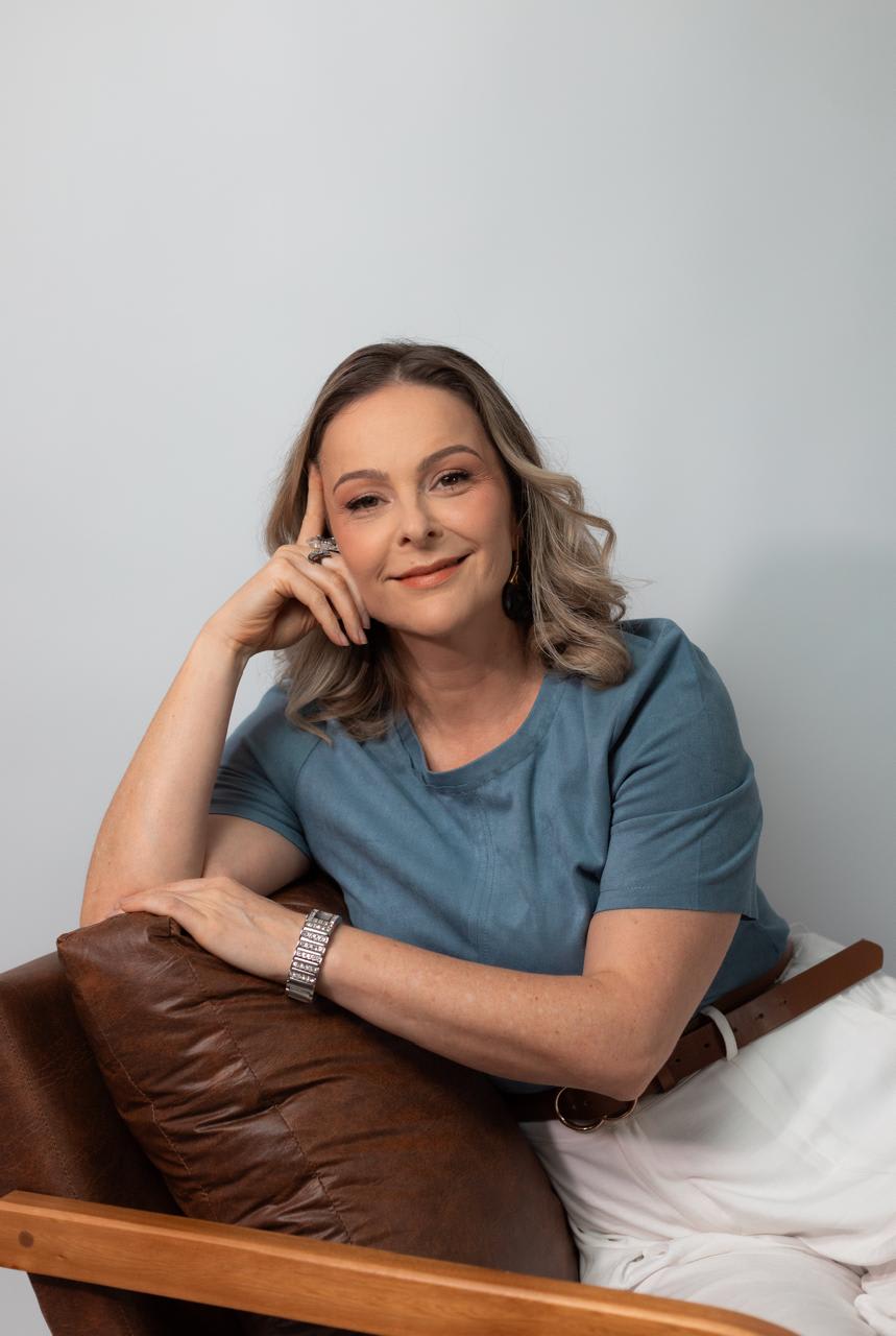 Juliane Bach em postura serena, com a mão apoiada no rosto, em retrato de presença