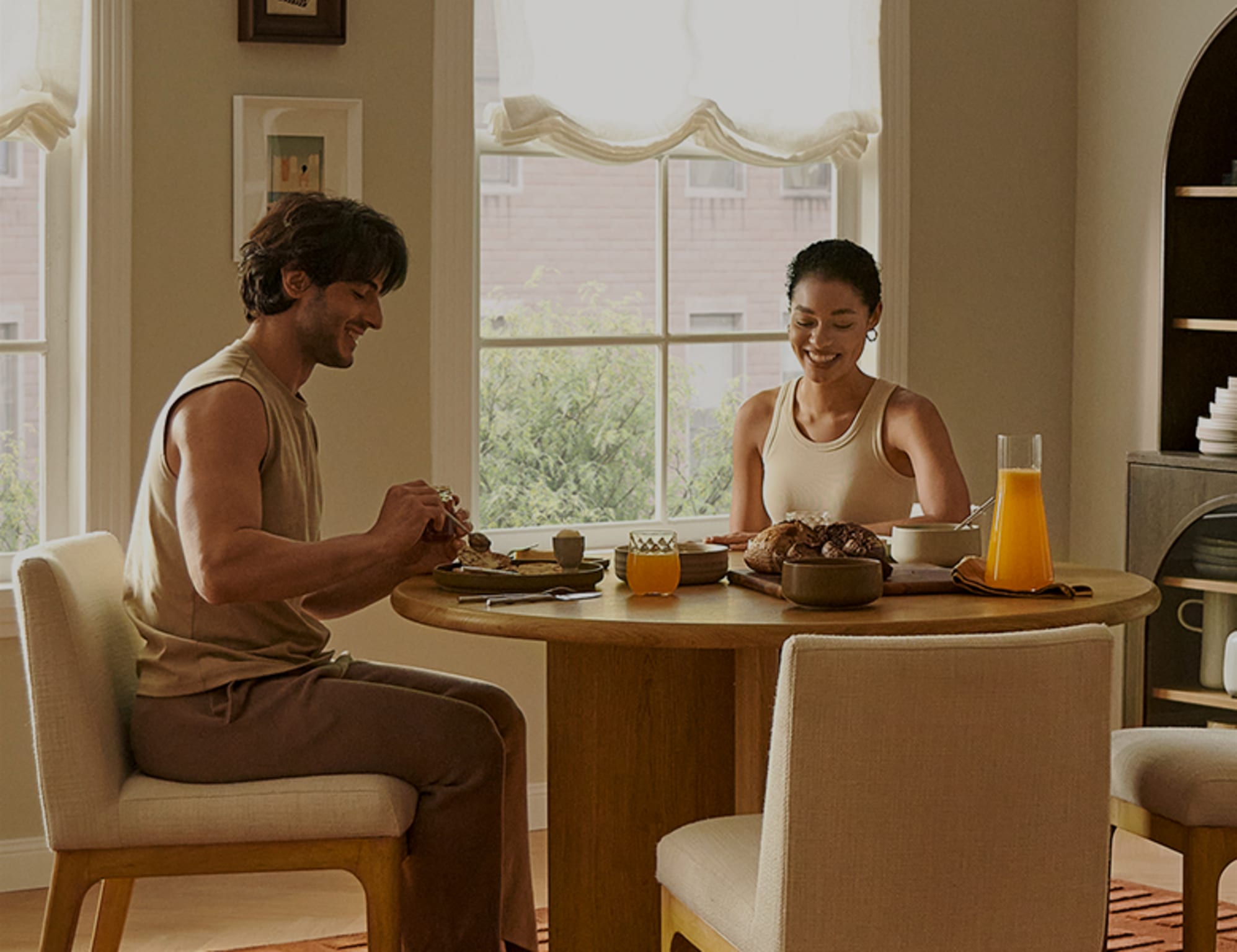 A man and woman sitting at a dining table while having food.