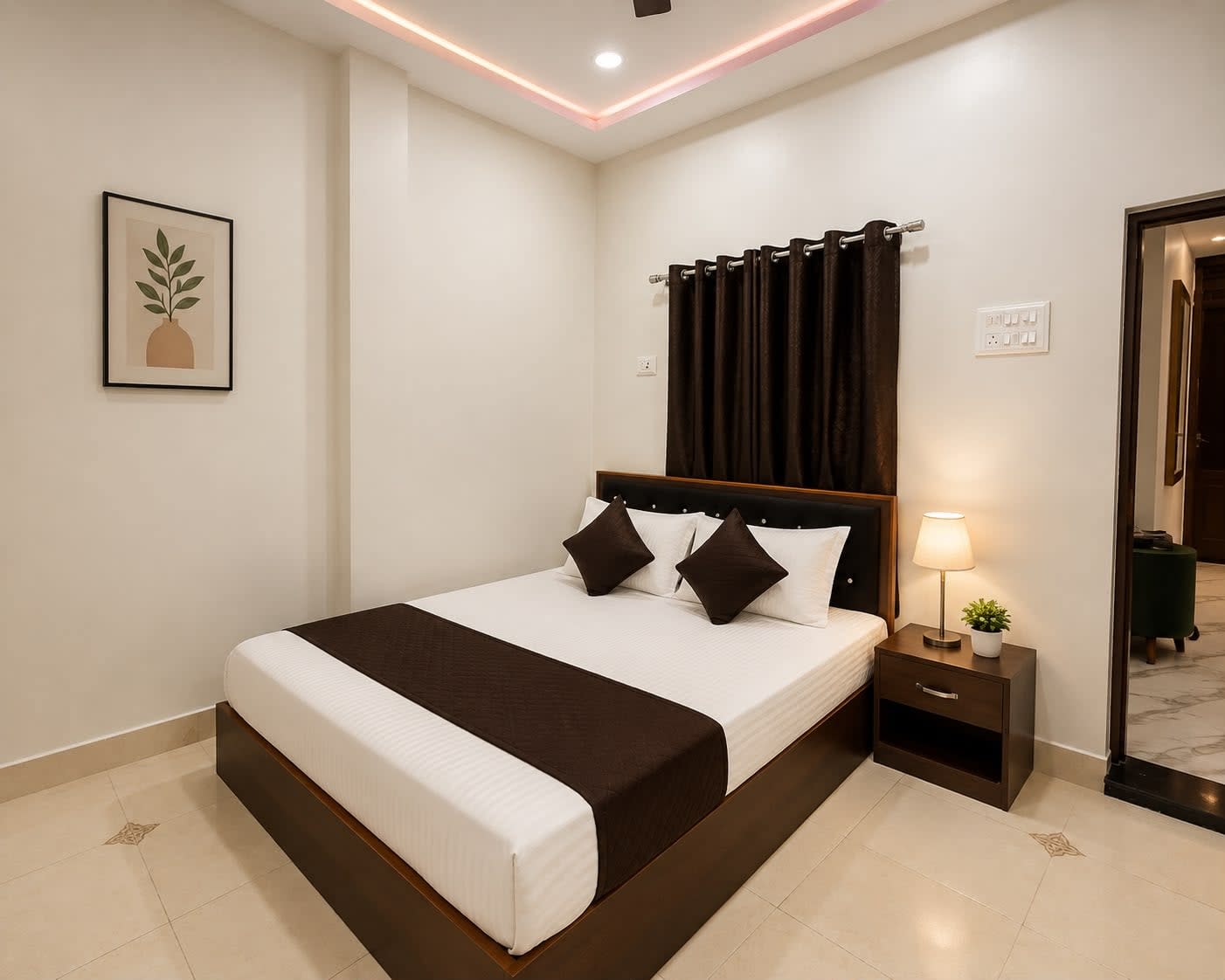 Bedroom 2 — Cozy Deluxe Room with warm bedside lamp, botanical wall art, and ambient false ceiling cove lighting