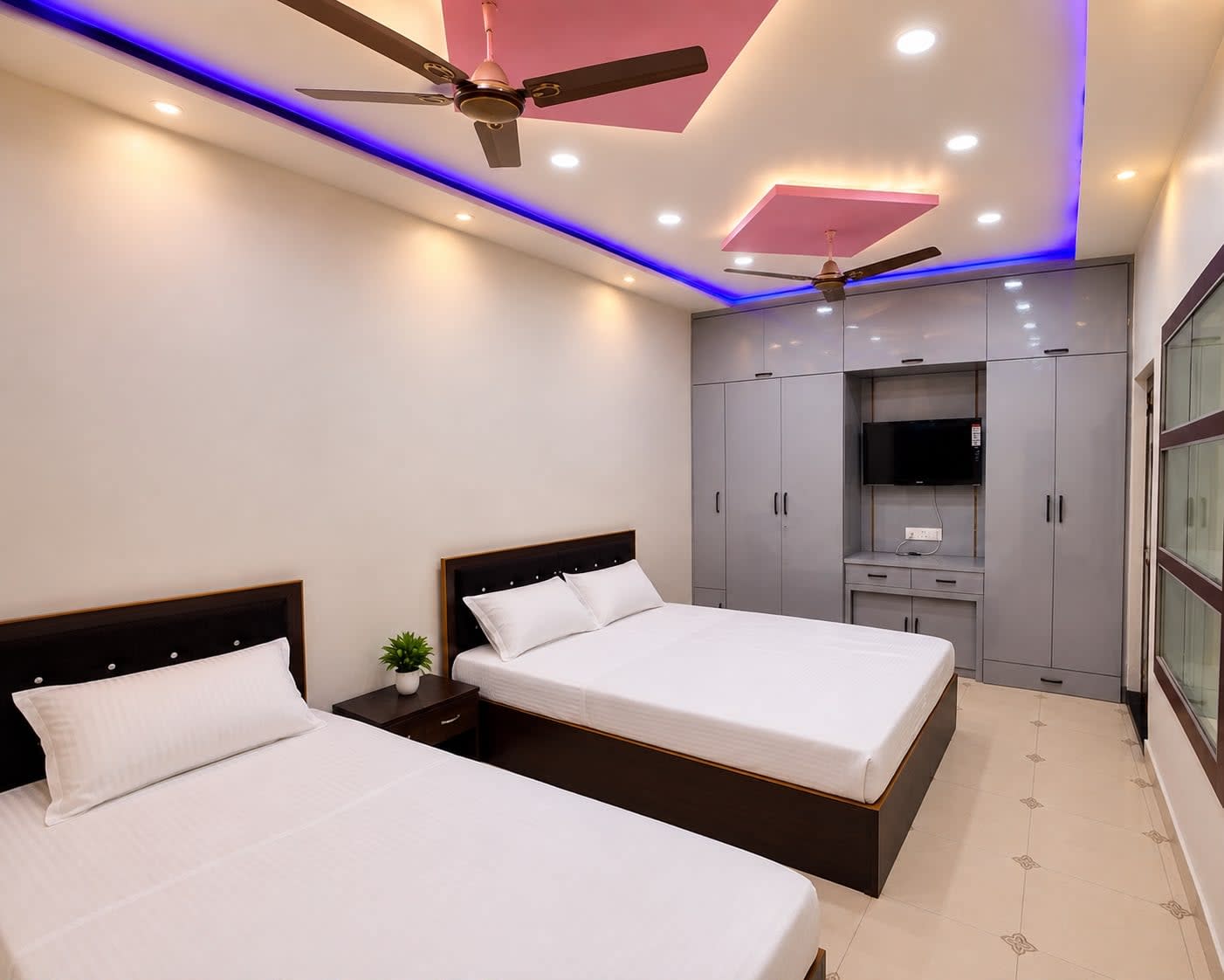 Family Bedroom 4 / Quad Suite — Double bed + single bed (sleeps 3), grey floor-to-ceiling wardrobes, wall-mounted TV, pink & blue ambient lighting