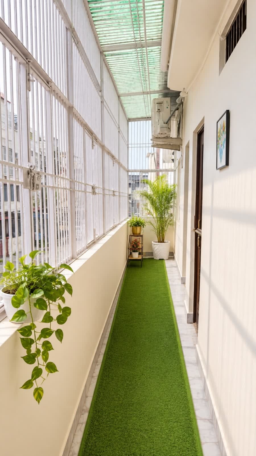 Private Green Balcony — Artificial turf runner, potted plants, white safety grill, skylight