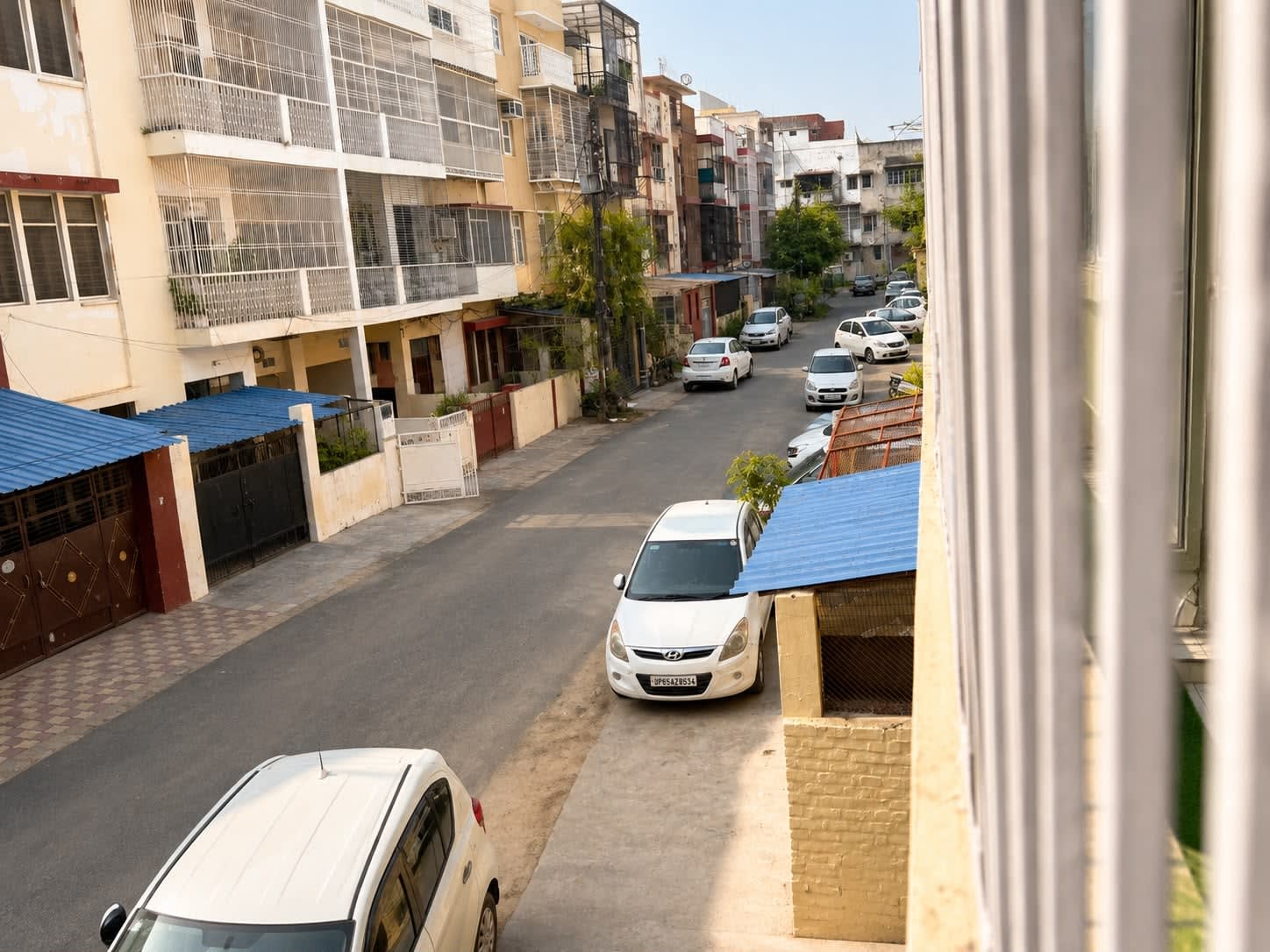 Shastri Nagar Neighborhood & Street View — Balcony view of peaceful tree-lined Shastri Nagar residential road with car parking